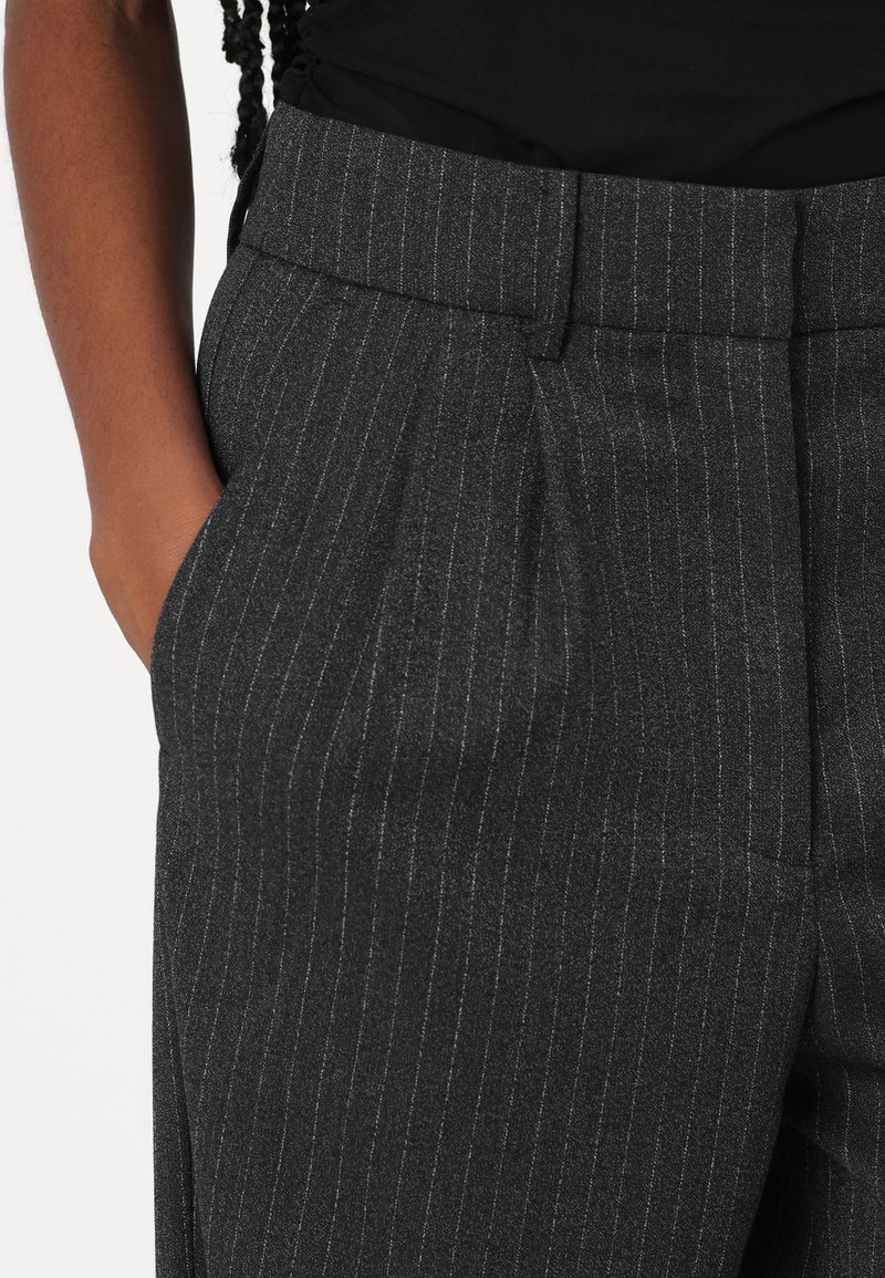 Graue Nadelstreifenhose mit einem taillierten Bund, ausgestattet mit Seitentaschen und einer glatten Textur. Das Material wirkt leicht und maßgeschneidert.