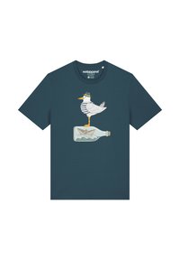 T-shirt bleu canard avec un motif d'une mouette portant une chemise rayée, se tenant sur une bouteille en verre avec un bateau en papier à l'intérieur.