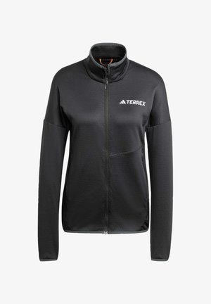 Juodas užtrauktukas striukė, pagaminta iš lygaus, lengvo audinio. Yra aukštas apykaklė, ilgos rankovės ir toninis logotipas ant krūtinės.