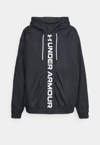 Svart huva vindjacka i lätt material, med en vit vertikal logotyp på framsidan och elastiska ärmslut.