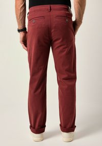 Vínové bavlněné kalhoty se rovný střih, ohrnovacími manžetami a dvěma zadními kapsami na knoflíkové zapínání. Hladká textura a jednoduchý design.