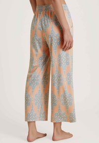 Pyjamabroek in perzik met een blauw intricaat bloemenpatroon, met een ontspannen pasvorm en een elastische tailleband. Rechte zoom; geen zichtbare zakken.