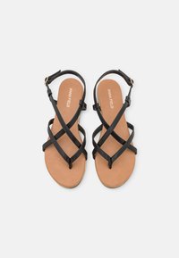Black cross-strap sandals with a smooth upper, a tan insole, and a gold-tone buckle. Flat sole for comfort and stability.