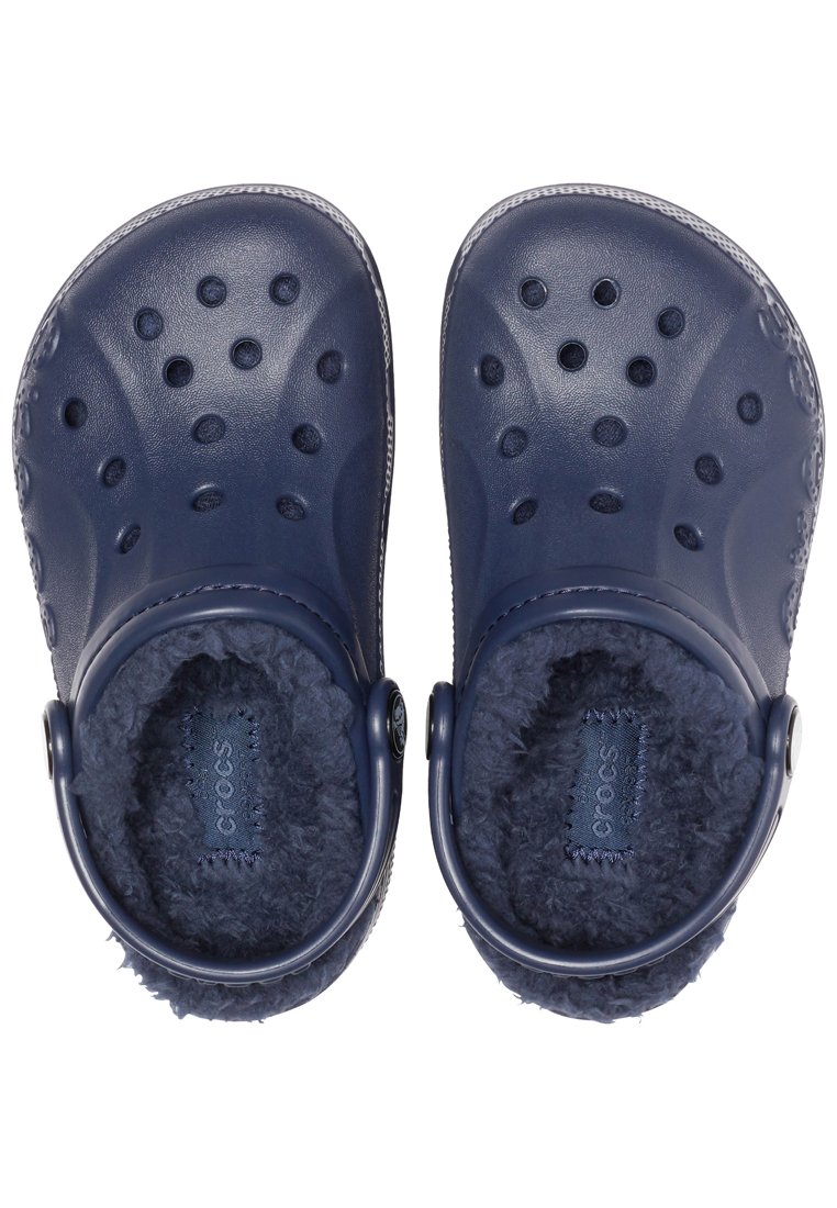 Crocs blu navy con esterno testurizzato, fori circolari e interno morbido e peloso. Dotati di una cinghia posteriore per una vestibilità sicura.