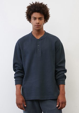 Dunkelblaues Langarm-Henley-Oberteil aus strukturiertem Stoff, mit einem V-Ausschnitt, einer Knopfleiste mit drei Knöpfen und gerippten Bündchen.