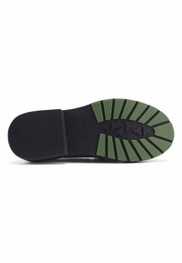 Suola di scarpa nera con caratteristiche di trazione in gomma verde e motivi testurizzati. Include dettagli di branding e una finitura liscia nera.