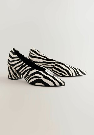 Talons aiguilles à imprimé zèbre, présentant un motif texturé noir et blanc, un talon épais et une silhouette élégante.