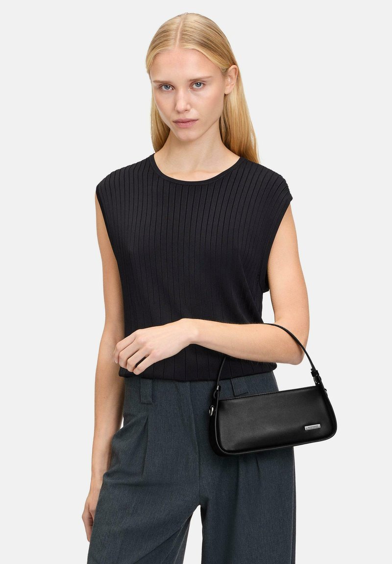Black leather handbag with a sleek, rectangular shape and a curved handle. Model wears a black ribbed top and gray high-waisted trousers.