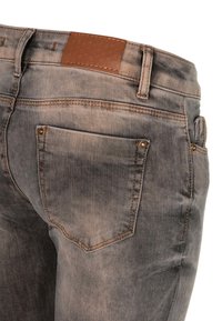 Slim-fit grijze denim jeans met een licht vervaagde textuur, voorzien van een leren label in bruin en twee achterzakken met gouden hardware accenten.