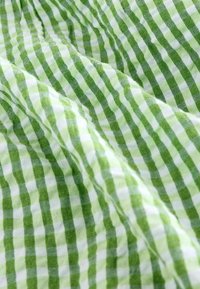 Zeleni i bijeli gingham materijal s mekom teksturom. Sadrži naizmjenične kvadratiće u dvije nijanse zelene boje s bijelom, stvarajući klasičan uzorak.