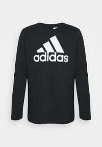 Czarna bawełniana koszulka z długim rękawem i okrągłym dekoltem. Z przodu duże białe logo Adidas. Gładka tekstura.
