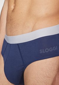 Marineblaue Boxershorts mit einem weichen, grauen Elastikbund. Mit einem Logo an der Seite und aus einem glatten Stoff mit einer engen Passform gefertigt.