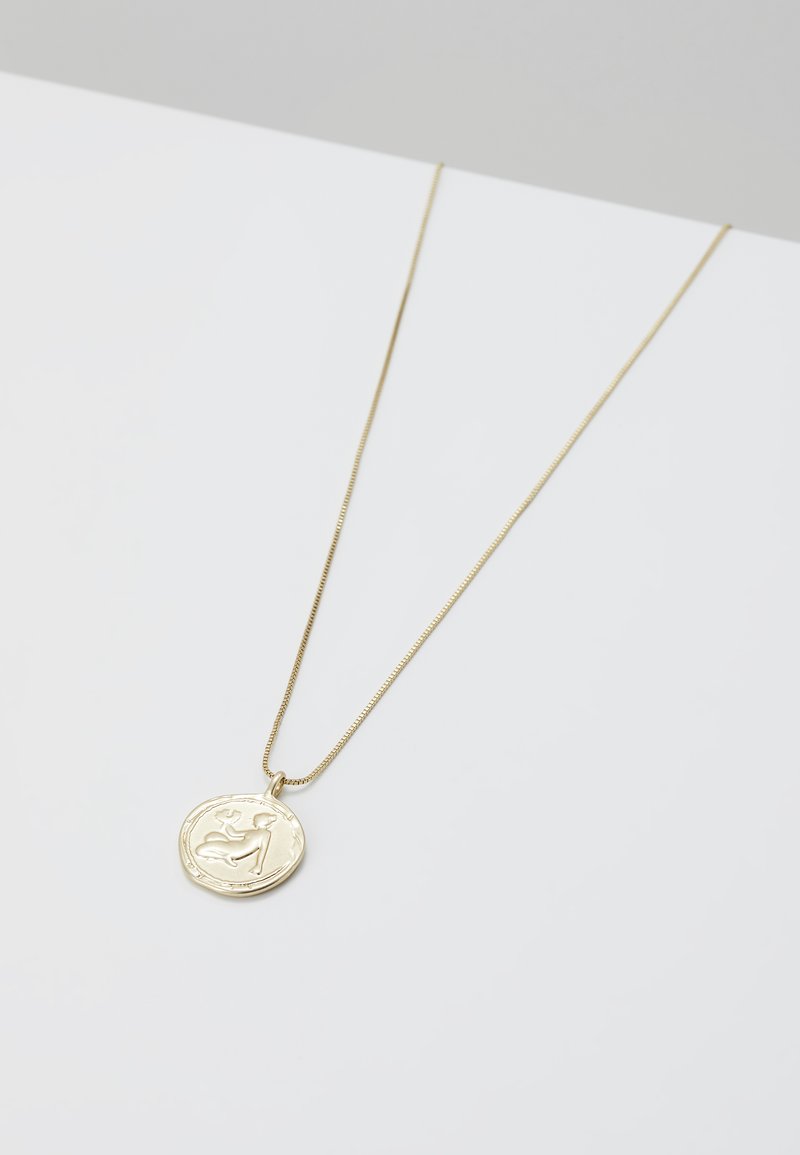 Collar de oro con una cadena delgada y un colgante circular que presenta un diseño en relieve. El colgante tiene un acabado texturizado y bordes suaves.
