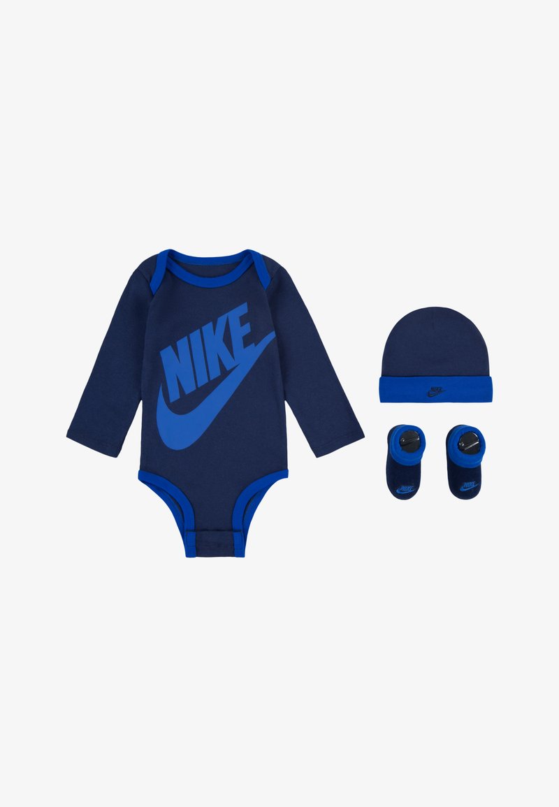 Sötétkék, hosszú ujjú bodi nagy kék Nike logóval, hozzá illő sapkával és cipőkkel párosítva. Puha pamutanyag.