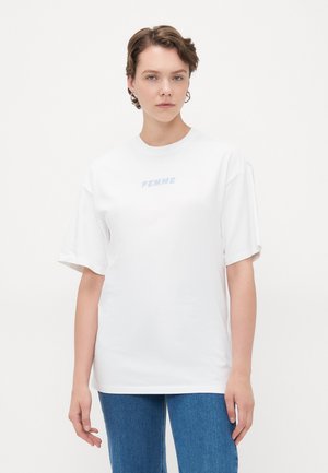 Hvit bomulls t-skjorte med oversized passform, rund hals og korte ermer. Har lys blå "FEMME" tekst på forsiden.