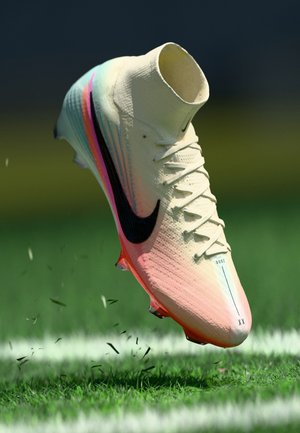 Futbalové kopačky Nike s krémovým zvrškom, gradientovými akcentmi v odtieňoch ružovej a modrej, čiernym swooshom, textúrovaným povrchom a špicatou špičkou.