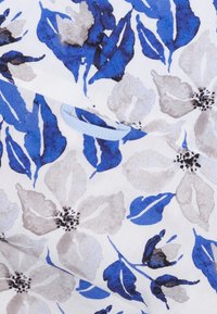 Bloemenstof met blauwe en grijze bloemen op een witte achtergrond, met een zachte textuur en een lichtblauwe accentlus.