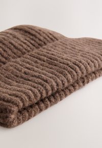 Brown, ribbed wool blanket folded neatly, featuring a textured surface and a soft appearance, ideal for warmth and comfort.