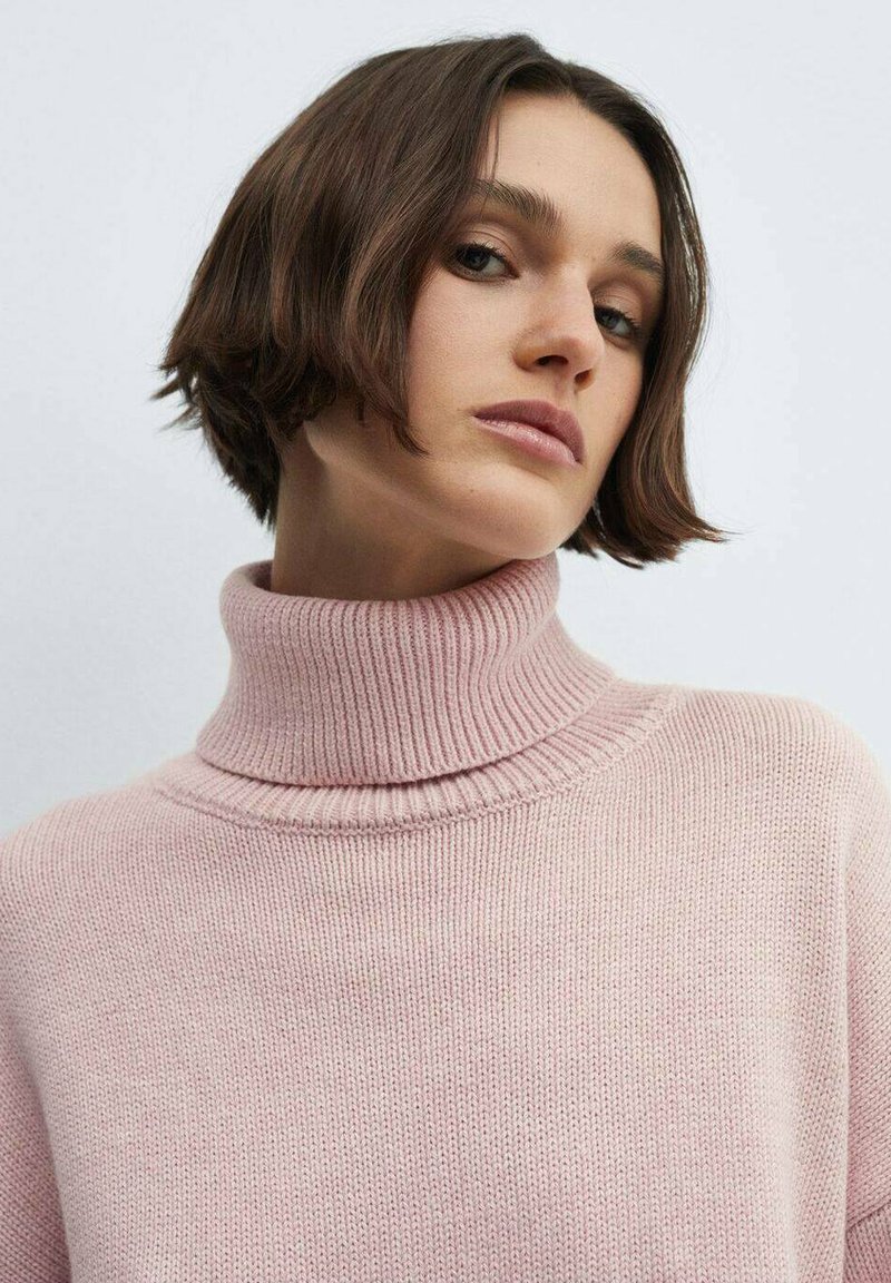 Helles rosa Turtleneck-Pullover mit geripptem Kragen und Textur. Weicher Strickstoff, der subtile Nähte zeigt und in einem lässigen Schnitt gestaltet ist.