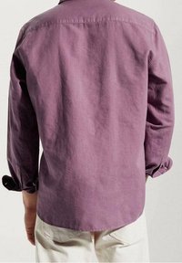 Camisa de manga larga de algodón en color malva, con un cuello tradicional, puños abotonados y un dobladillo recto, mostrada desde la parte posterior.