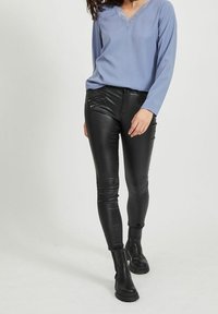 Ljusblå långärmad blus med V-ringning och spetsdetaljer, i kombination med svarta tights i konstläder och svarta ankelstövlar.