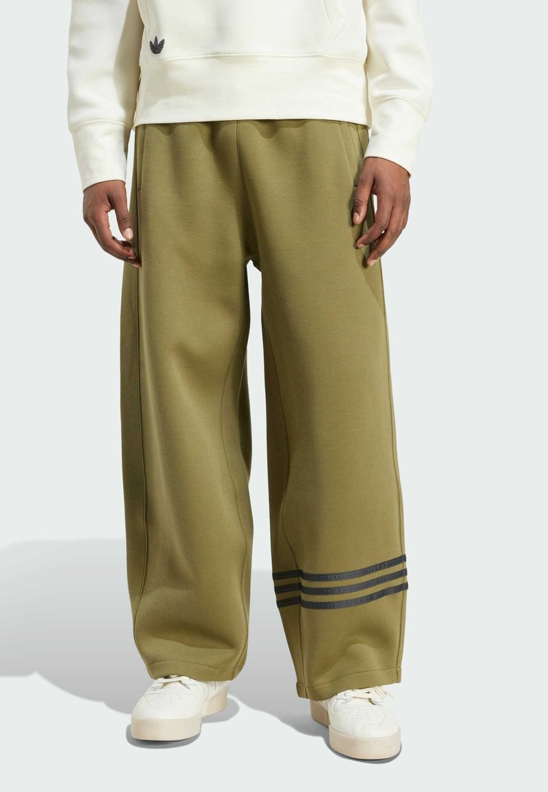 Olivově zelené tepláky vyrobené z měkké tkaniny, s širokými nohavicemi, postranními švy a třemi černými pruhy na spodní části nohavic.