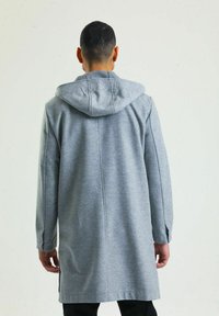 Grau hoodie Mantel mit langer Silhouette, hergestellt aus einem weichen Stoff. Verfügt über seitliche Schlitze und Knopfdetails an den Ärmeln.