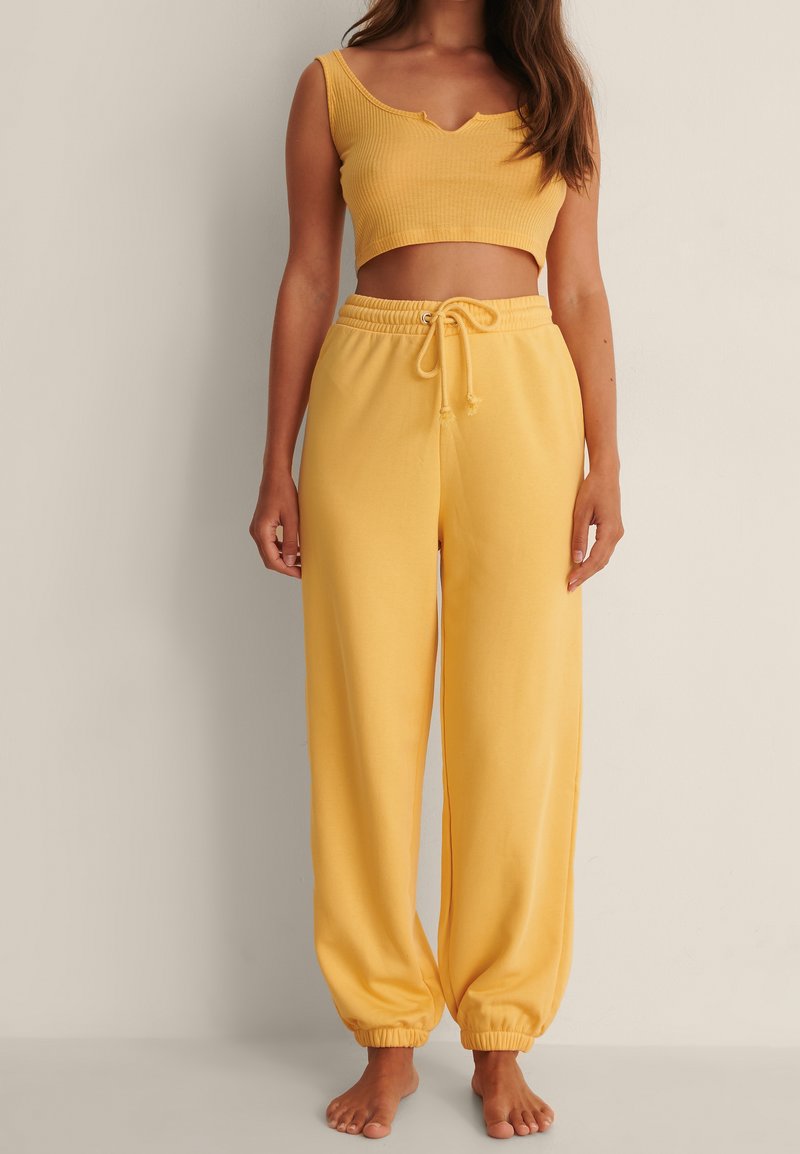 Yellow ribbed crop top with a V-neckline paired with matching yellow drawstring wide-leg pants. Both items feature a soft texture.
