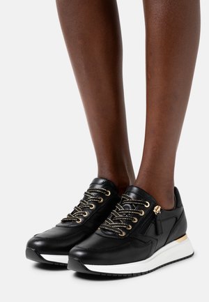 Sneakers in pelle nera con accenti dorati, caratterizzati da una suola bianca, occhielli color oro e dettagli testurizzati sulla parte superiore.
