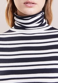 Maglione girocollo a righe blu navy e bianco, con righe orizzontali, texture morbida e design aderente attorno al collo.