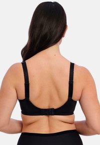 Sostén negro con tirantes ajustables y cierre de gancho y ojal. Tejido suave con un diseño sencillo que muestra un estilo minimalista.