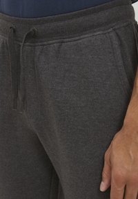 Gray sweatpants made of soft fabric, featuring an elastic waistband with drawstring, side pockets, and a relaxed fit.