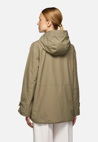 Khaki huva jacka med avslappnad passform. Slen, vattenavvisande tyg, synliga söm detaljeringar och justerbara ärmremmar.