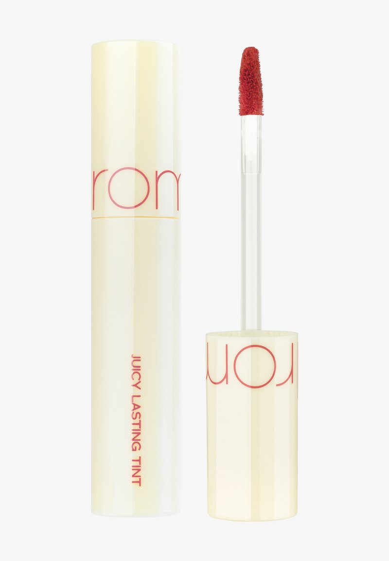 Tienne à lèvres liquide avec un tube cylindrique jaune brillant comportant un texte rouge. Comprend un applicateur transparent avec une pointe douce et duveteuse.