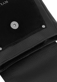 Black leather bag with textured surface, a flap secured by a silver magnetic snap button, and visible stitching and metallic rivets.