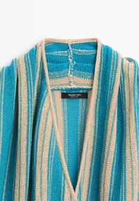 Gestrickte Strickjacke mit vertikalen blauen und beigen Streifen und Schalkragen, mit einem schwarzen Massimo Dutti Etikett innen am Halsausschnitt.