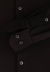 Zwarte longsleeve shirt met een gladde textuur, voorzien van grijze knopen, gestructureerde manchetten en een hoekige kraag.