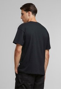 Sort bomulds T-shirt med afslappet pasform, korte ærmer og rund halsudskæring, med en ensfarvet ryg og uden synlige logoer eller mønstre.