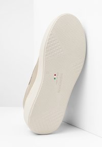 Suela de zapatilla beige con superficie de goma texturizada, que presenta patrones geométricos en relieve y marca. Talla marcada como 37, fabricada en Italia.