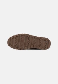 Semelle en caoutchouc marron avec une texture antidérapante, présentant des motifs en zigzag, et la marque "ROXY" affichée en évidence au centre.