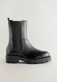 Musta nahkasaapas nilkkamittaisella elastisella sivupaneelilla, teksturoidulla pohjalla ja pyöristetyllä varpaalla. Varustettu vetonauhalla ja tyylikkäällä ompeluyksityiskohdalla.