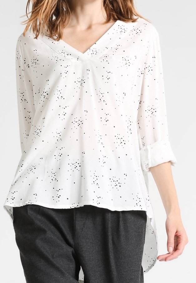 Blusa blanca con escote en V, diseño moteado negro, mangas largas con puños enrollados y corte holgado. Tela suave y ligera.