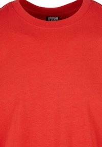 Gros plan d'un t-shirt rouge Urban Classics montrant le col rond et la texture du tissu.