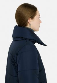 Granatowa kurtka puchowa z wysokim kołnierzem i pikowanym wzorem, z grubo podszewkowanym wnętrzem i gładkim wykończeniem. Elegancki i nowoczesny design.