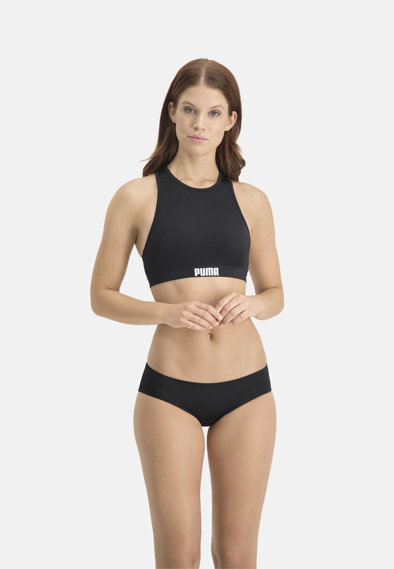 Schwarzer Sport-BH mit ärmellosem Design und hohem Kragen, mit einem weißen "PUMA"-Logo am Bund. Kombiniert mit schwarzen Bikini-Höschen.