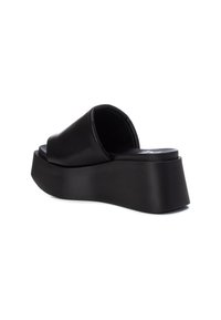 Sandalias de plataforma negras con parte superior sintética suave y una correa ancha. Diseño de punta redondeada, suela contorneada y audaz, y acabado mate.