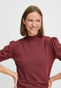 Bordoo lõngast särk kõrge kaelusega, lühikeste puffvarrukate ja klammerdava siluetti. Sile tekstuur koos ribakujundusega krae juures.
