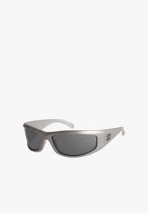 Sport sunglasses with a matte silver frame, wrap-around design, dark tinted lenses, and logo accent on the arm.