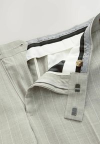 Pantaloni a righe grigio chiaro con chiusura a bottone, zip e tessuto testurizzato. La vita interna è dotata di elastico e bordino nero a contrasto.