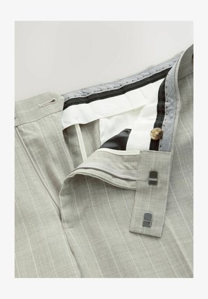 Világosszürke csíkos nadrág, gombos záródással, cipzárral és texturált anyaggal. A belső derékrész rugalmas, kontrasztos fekete díszítéssel rendelkezik.